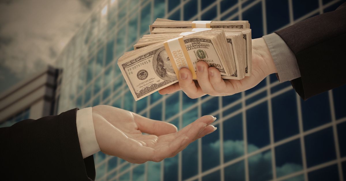 Person handing a stack of cash to another individual, representing legal fees or settlement payment.