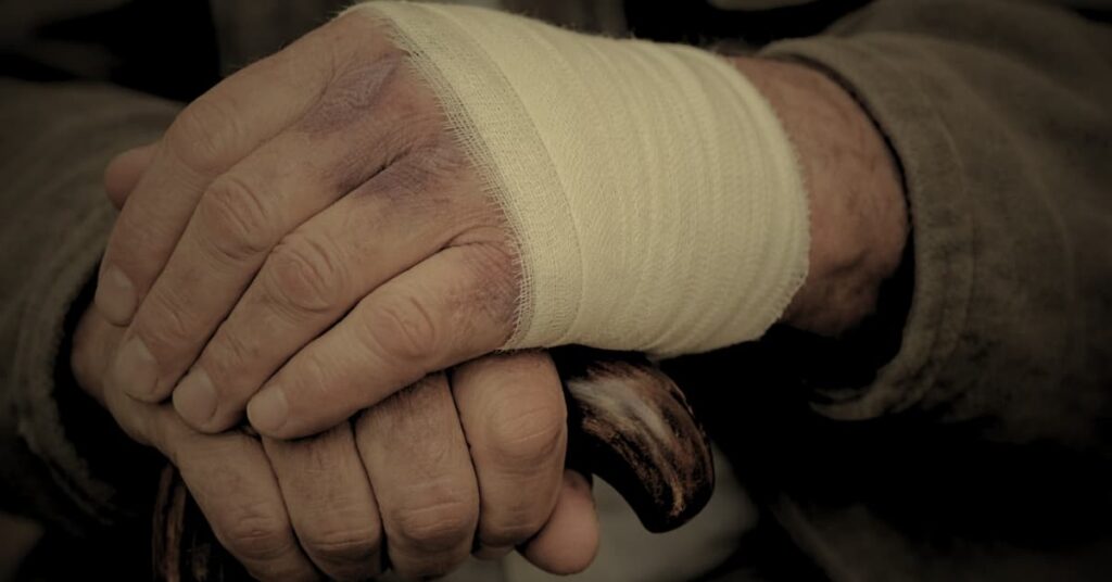 Elderly nursing home resident being assisted by a caregiver after a fall injury