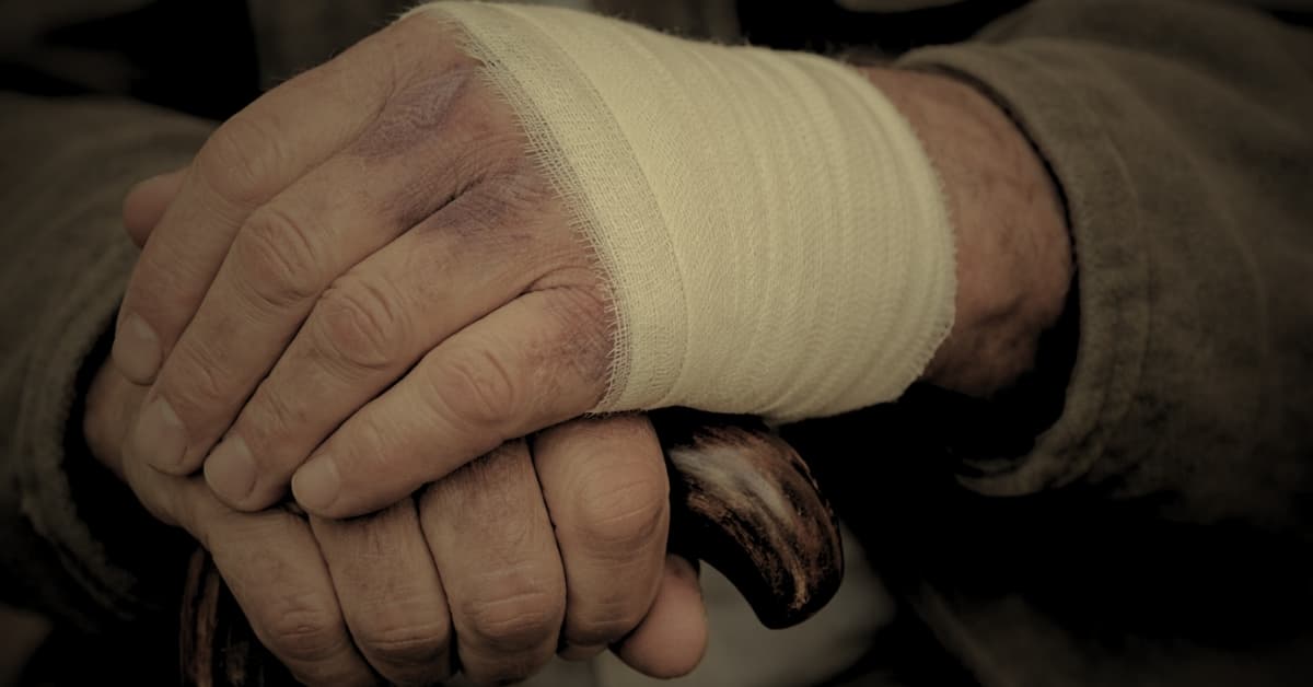 Elderly nursing home resident being assisted by a caregiver after a fall injury