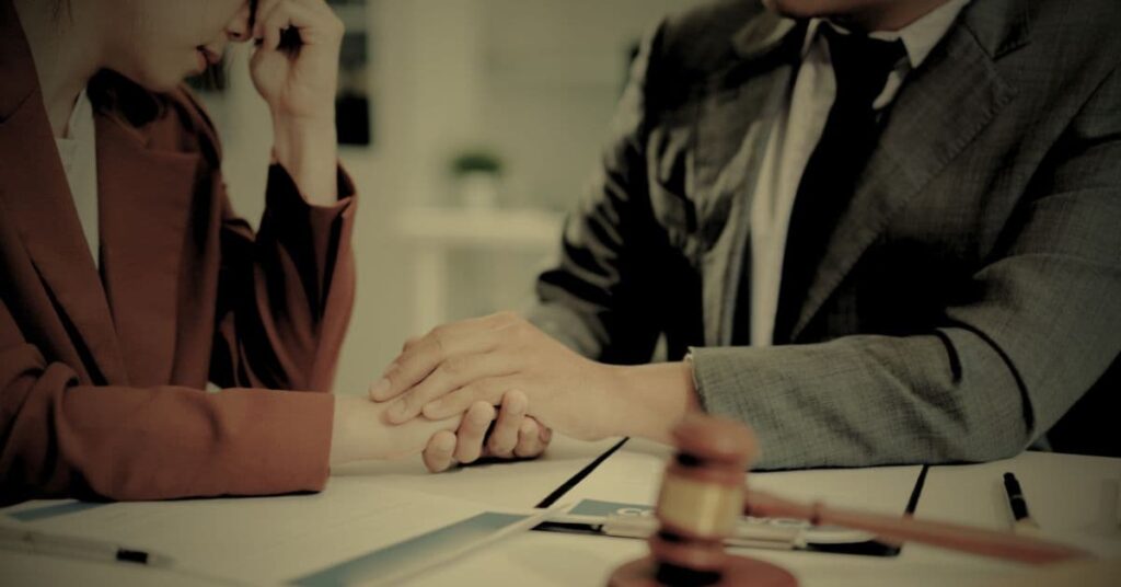 Lawyer shaking hands with a client at a table in a patient abandonment consultation
