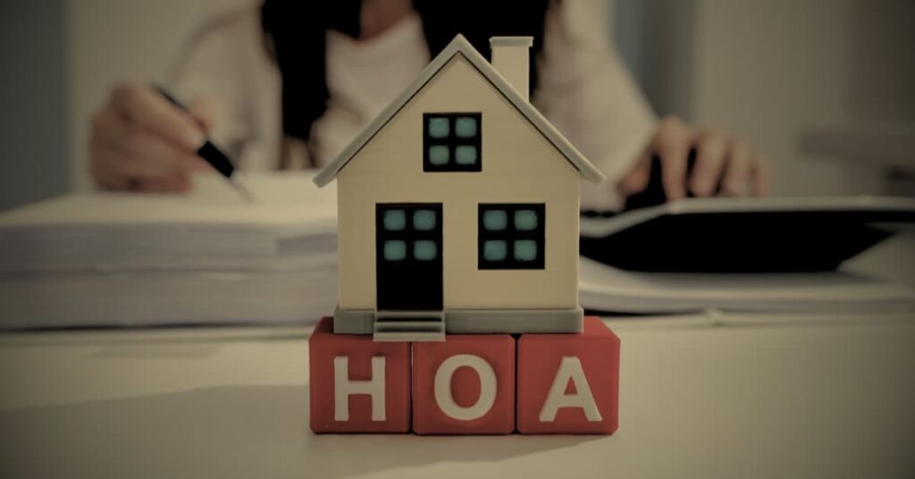 HOA fees in Florida — house model on HOA blocks with homeowner reviewing documents